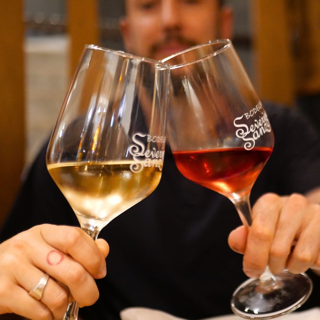 Dos copas de vino blanco y tinto chocan en un brindis